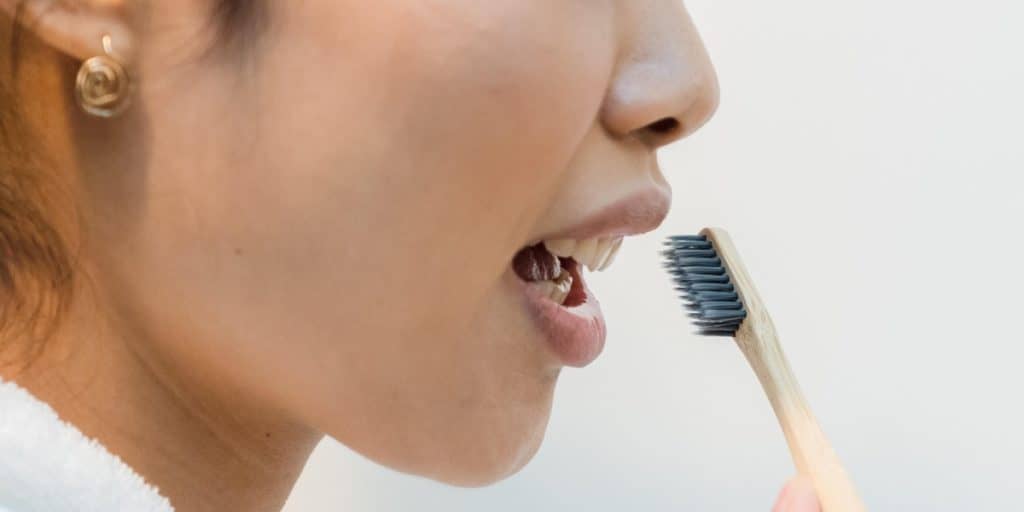 Close up of a woman's side profile while brushing her teeth.