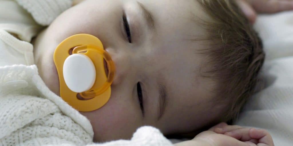 Close up image of sleeping baby with a pacifier.