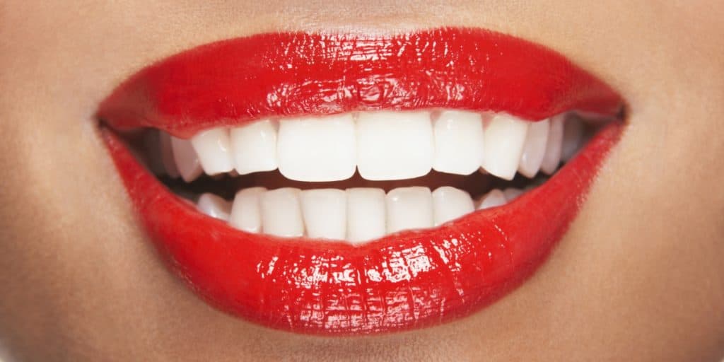 Close up smile showing white teeth and lips with lipstick.