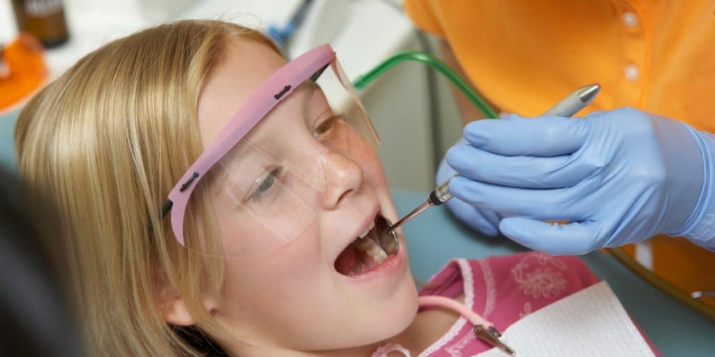 Young patient wearing dental eye protection during check up.