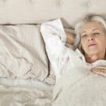 Senior woman, candidate for dentures, sleeping in bed.