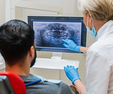 Dentist showing digital dental X-ray result to male patient.