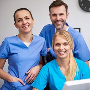Two female and one male dental professional in a dental office.