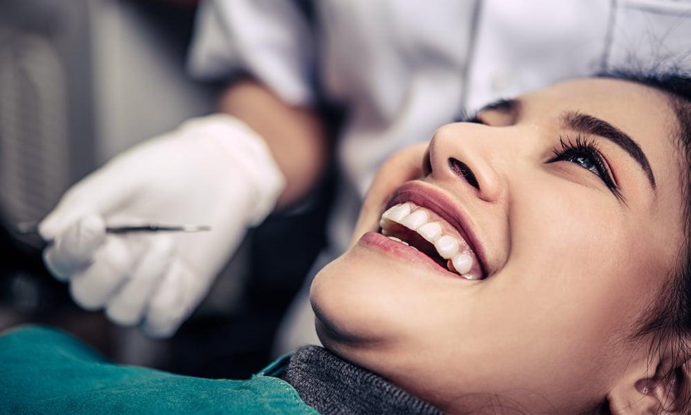 Grinning patient looking up at dental professional holding a dental tool for bonding.