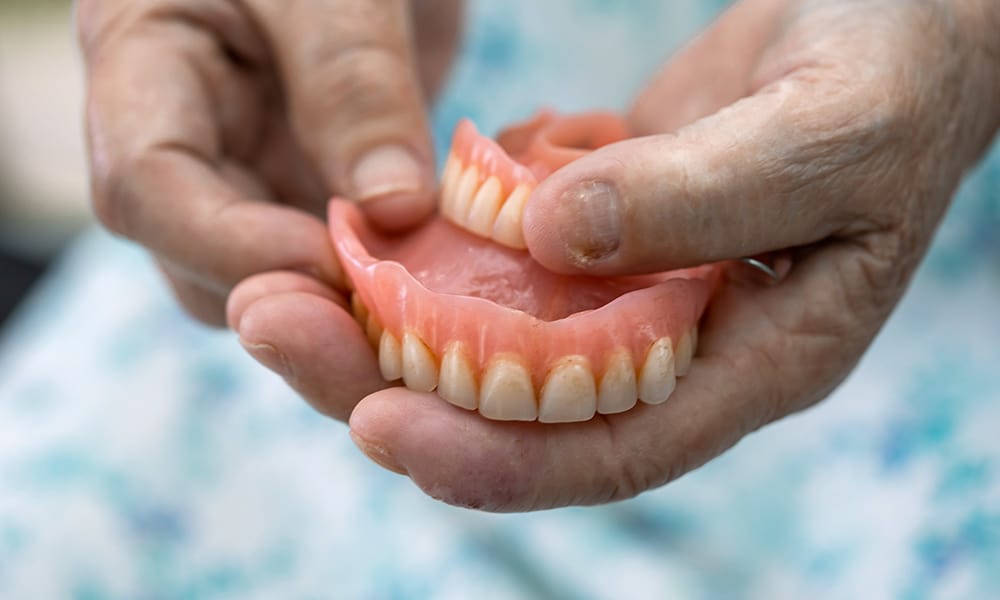 Senior patient holding full and partial dentures.