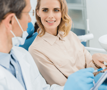 Female patient consulting the dentist holding a clipboard at oral care clinic.