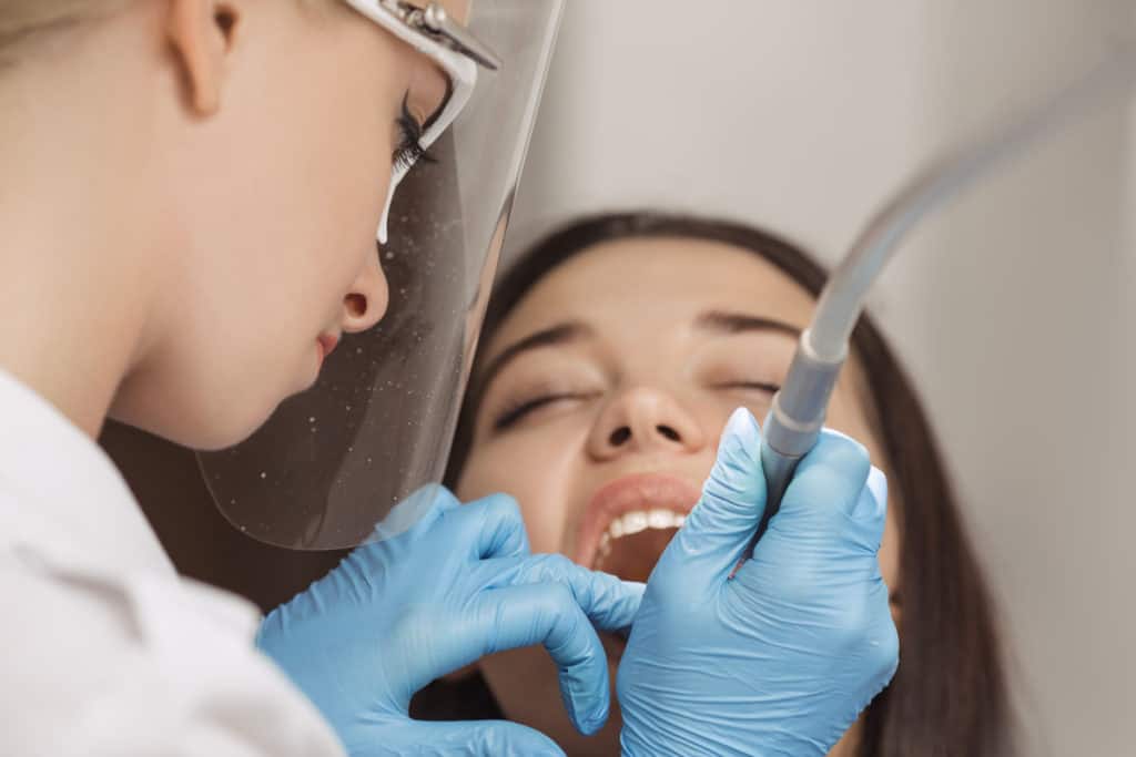 Dentist doing a dental procedure on female patient.