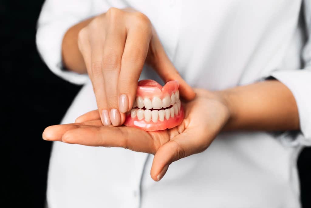 A dentist holding a complete set of dentures.