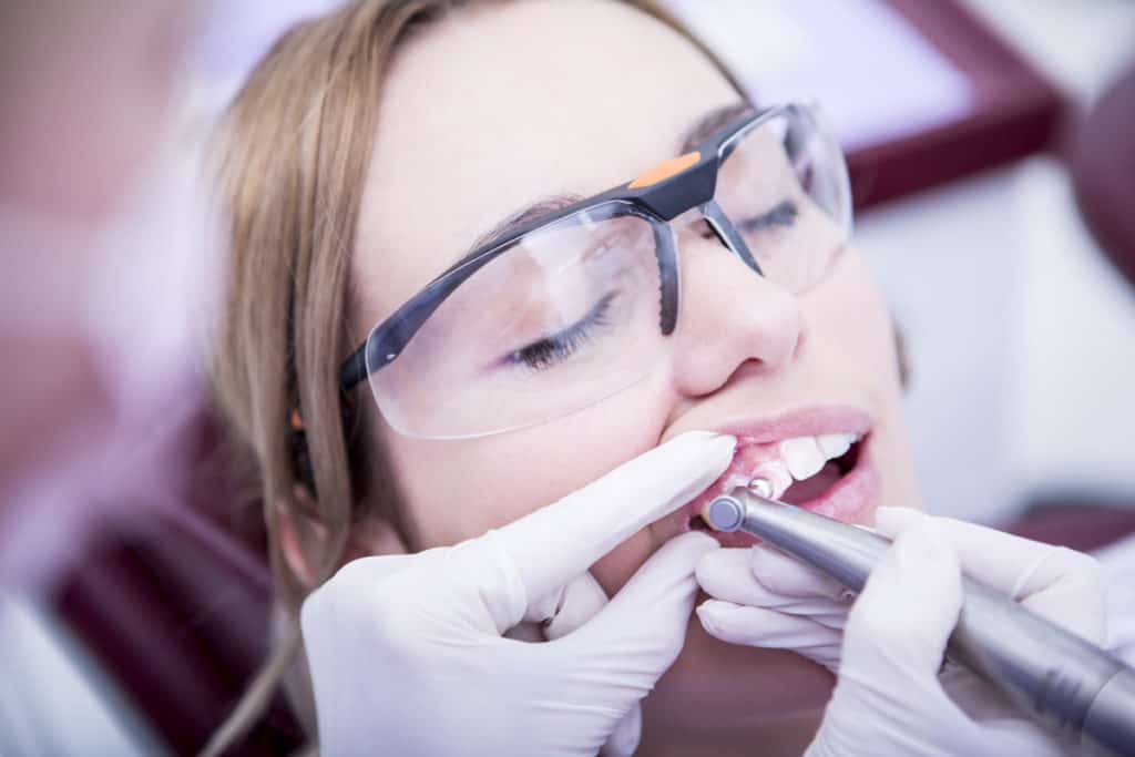 Female patient wearing protective glasses receiving a dental procedure.